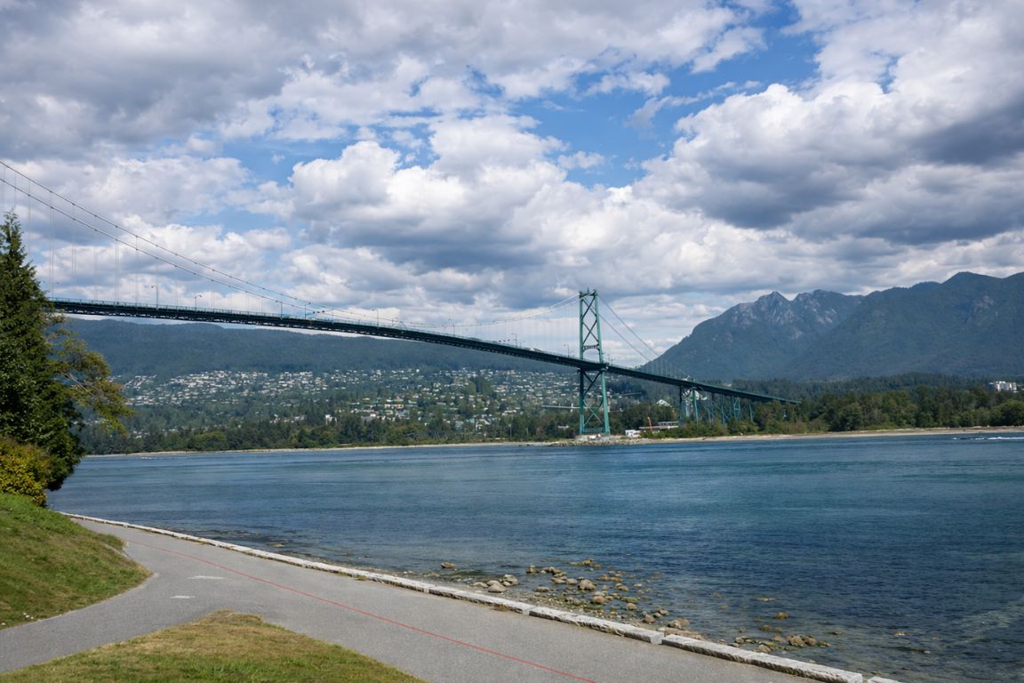 Lions Gate Bridge over Burrard Inlet with coastal mountains and waterfront path during a Vancouver Canada Tours excursion